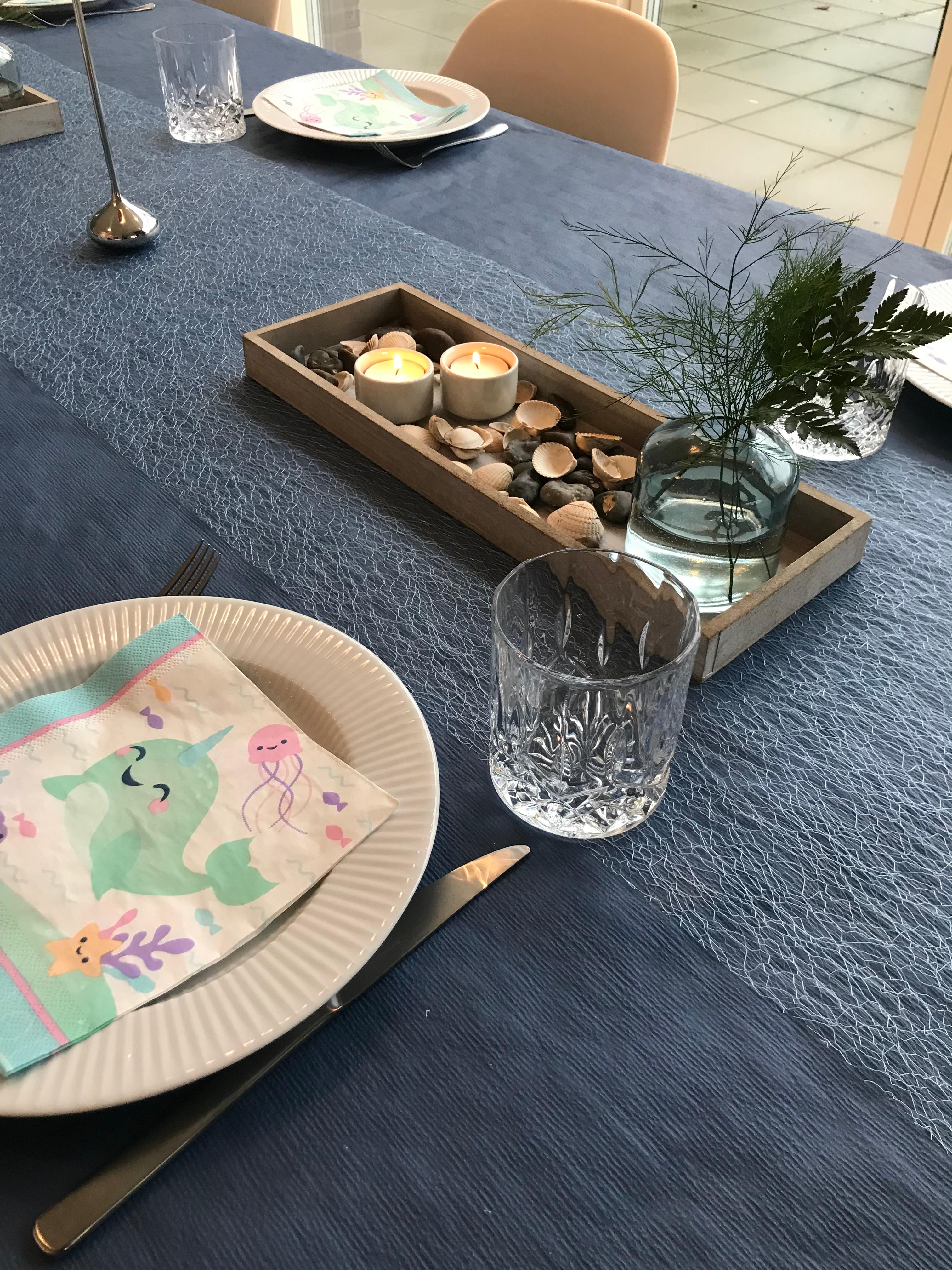 Blue vases with seashells and greenery on the party table