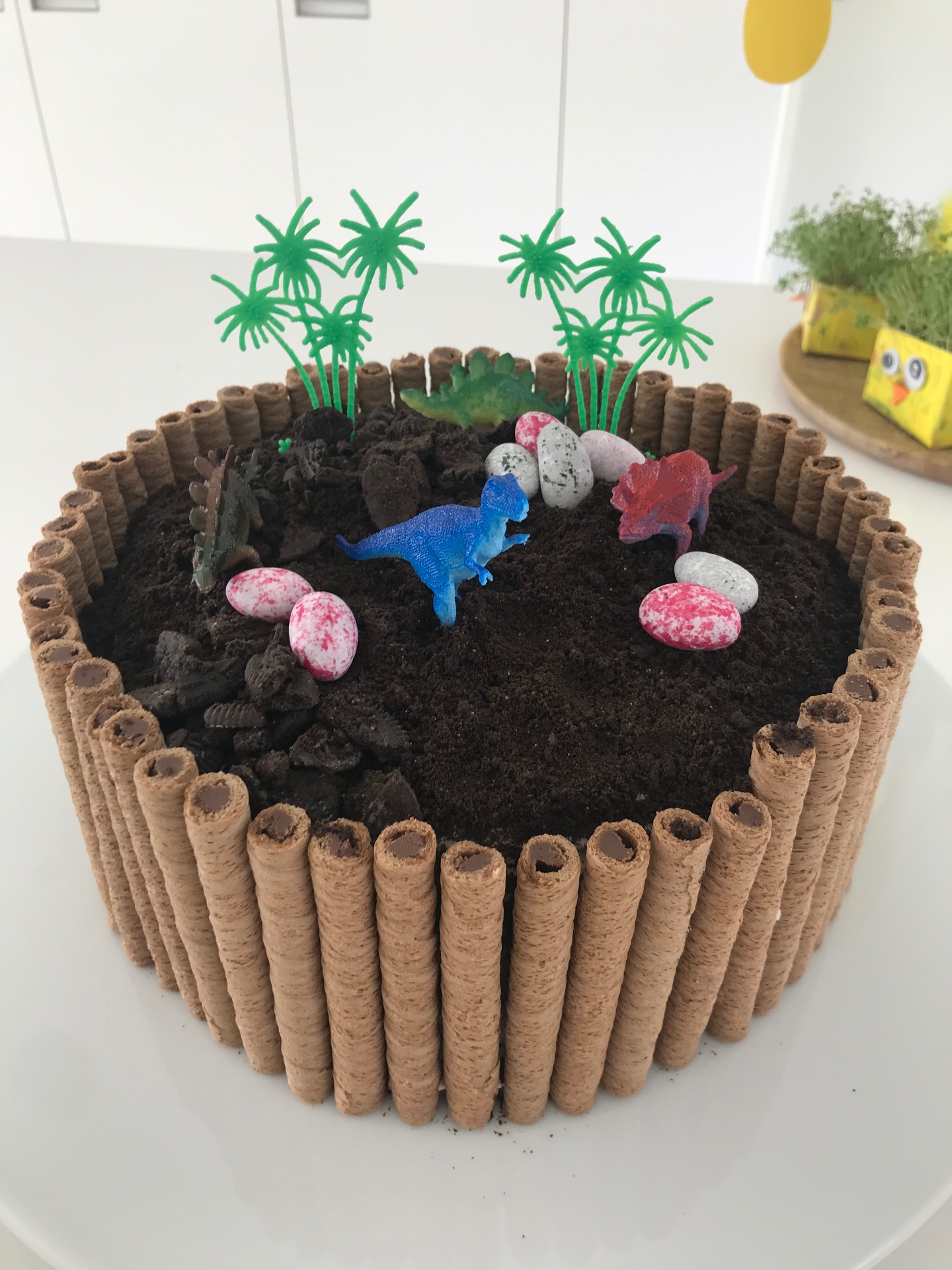 Dinosaur birthday cake with wafer-roll logs, chocolate soil, and toy dinosaurs
