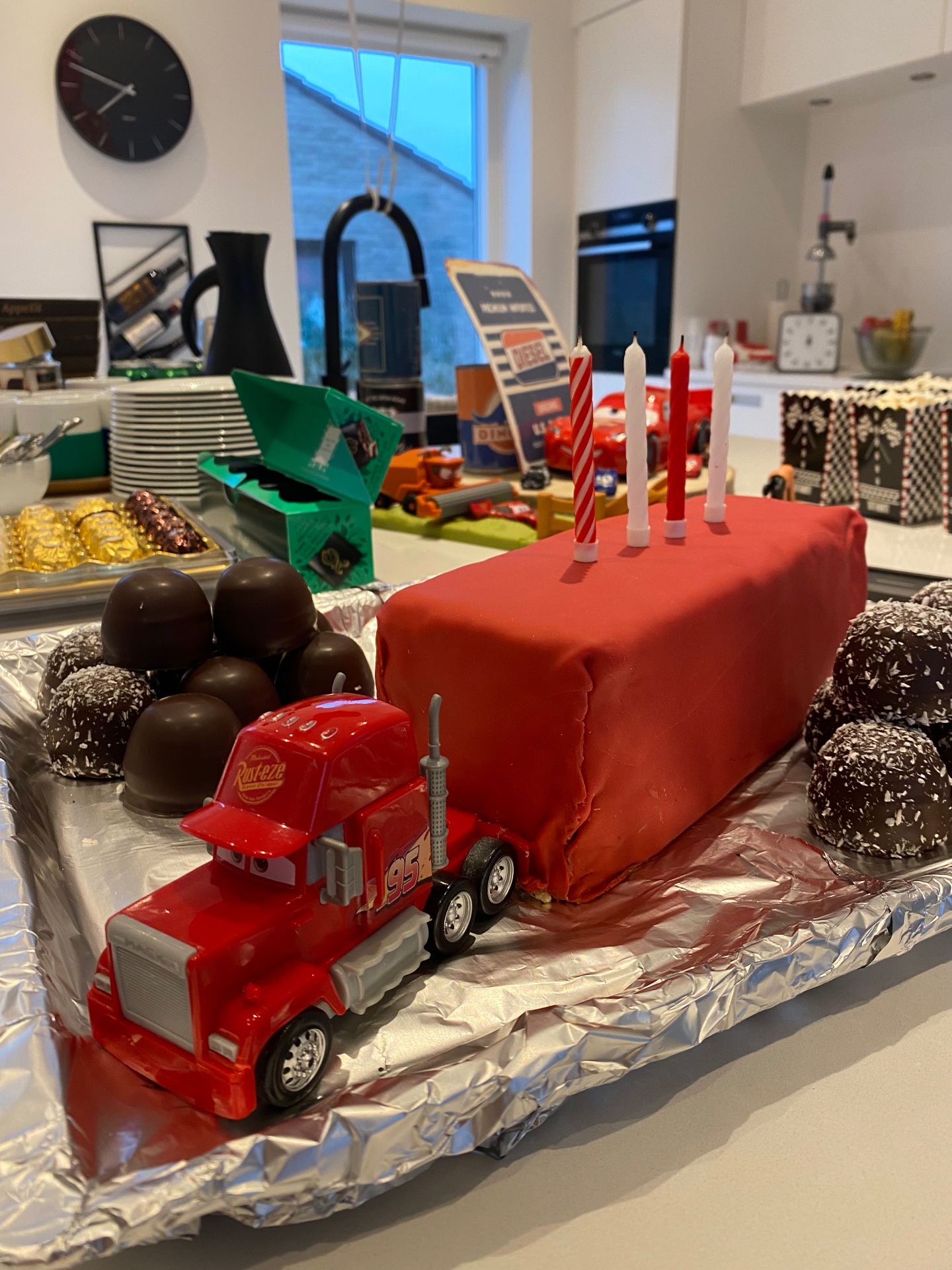 Nærbillede af en enkel rød fondantkage som trailer bag en Mack-legetøjslastbil
